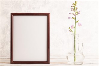 Wooden frame with hosta flowers in glass vase on gray concrete background. side view, copy space,
