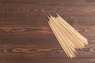 Japanese buckwheat soba noodles on brown wooden background. Top view, flat lay, copy space