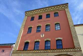 View of a historic red brick building with the nameplate 'Torres Daniela' under a blue sky, Torre