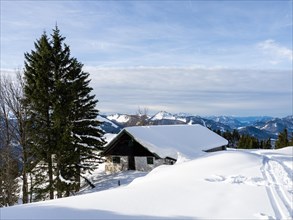 Winter atmosphere, snow-covered landscape, snow-covered alpine peaks, alpine hut on the