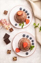 Chocolate jelly with strawberry and blueberry on gray concrete background and linen textile. top
