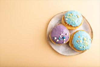 Purple and blue glazed donut on orange pastel background. top view, flat lay, copy space.