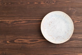 Empty blue and gold ceramic plate on brown wooden background. Top view, copy space, flat lay