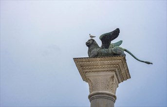 Winged lion of Saint Mark, old bronze statue on a column in San Marco square, famous tourist
