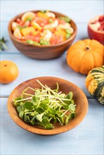 Sunflower microgreen sprouts and vegetarian fruit salad of pumpkin, tangerine, pomegranate,