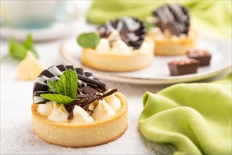 Sweet tartlets with chocolate and cheese cream with cup of coffee on a gray concrete background and