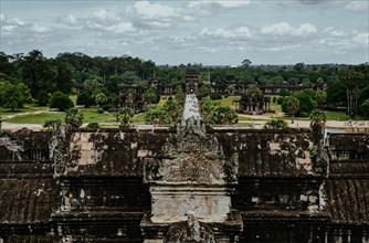 View of the historic Angkor Wat temple complex with lush trees under a cloudy sky. Siem reap,