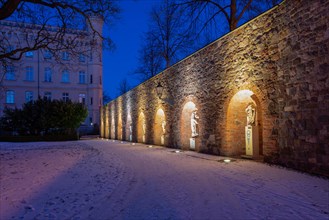 Illuminated arches with statues, historic city wall in the garden of the Moellenvogtei, dusk with