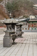 Two ornate metal incense candle burners on patio of Guinsa temple building in South Korea