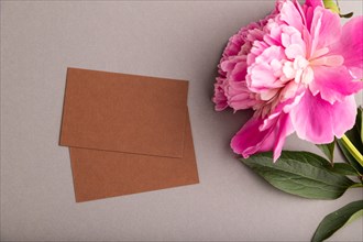 Brown business card with pink peony flowers on gray pastel background. top view, flat lay, copy
