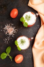 Tomato juice with basil, himalayan salt and sour cream in glass on a black concrete background with