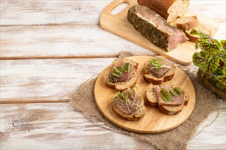 Bread sandwiches with jerky salted meat, sorrel and cilantro microgreen on white wooden background