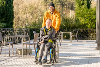 Relaxed disabled man with wheelchair and friends strolling in an urban park