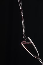 A champagne glass is filled with rose champagne, dark background