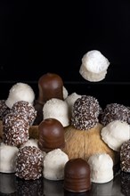 Pile of different chocolate kisses on a dark background, coconut half, one flying