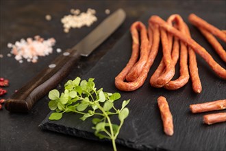 Traditional polish smoked pork sausage kabanos on a slate cutting board with salt and pepper on