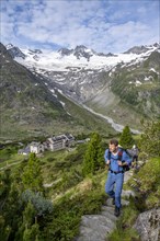 Two mountaineers on a hiking trail in a picturesque mountain landscape with alpine roses, in the