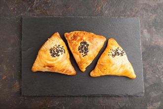 Homemade asian pastry samosa on black concrete background. top view, flat lay, close up