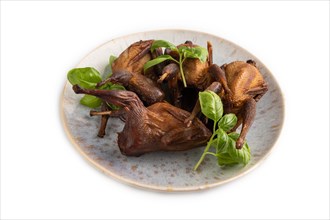 Smoked quails on a ceramic plate isolated on white background. Side view, close up
