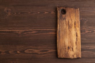 Empty rectangular wooden cutting board on brown wooden background. Top view, copy space, flat lay