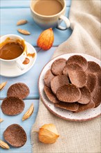 Chocolate chips with cup of coffee and caramel on a blue wooden background and linen textile. side