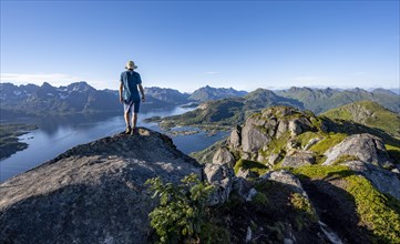 Mountaineer on the summit of Dronningsvarden or Stortinden, mountains and fjord Raftsund,