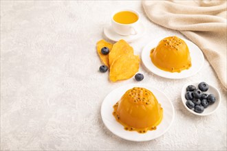 Mango and passion fruit jelly with blueberry on gray concrete background and linen textile. side