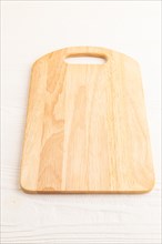 Empty rectangular wooden cutting board on white wooden background. Side view, close up