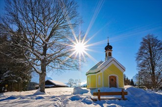 Backlit photograph of the snow-covered chapel Maria auf den Buckelwiesen in the Werdenfelser Land