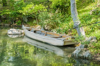 Wooden row boat at shore of lake in Japanese Shukkeien Gardens in Hiroshima, Japan, Asia