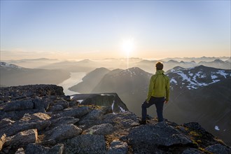 View of mountains and fjord Faleidfjorden, sun star at sunset, mountaineer at the summit of Skala,