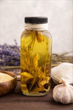 Sunflower oil in a glass jar with various herbs and spices, lavender, sesame, rosemary on a brown