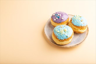 Purple and blue glazed donut on orange pastel background. side view, copy space. Breakfast,