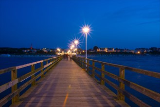 Nocturnal pier with illuminated street lamps and star effect, illuminated pier with strolling