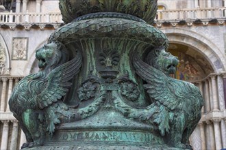 Old street ornament with winged lions and San Marco Basilica in the background, in St. Mark Square,