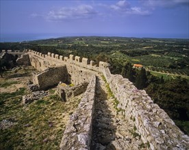 Fortress walls stretching over hilly terrain with lush vegetation, Chlemoutsi, High Medieval