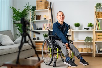 Disabled man in wheelchair recording vlog using digital camera at home