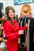 Vertical portrait of a woman trying on warm hat in a vintage clothes store