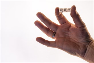 Male hand holding letter cubes forming the word anger, white background, studio shot, Germany,