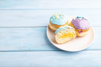 Purple and blue glazed donut on blue wooden background. side view, copy space. Breakfast, morning,