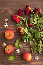 Withered, decaying, roses flowers and apples on brown wooden background. top view, flat lay, close