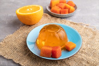 Papaya and orange jelly on gray concrete background and linen textile. side view, close up