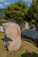 Large granite boulder in front of white picket fence in public rock garden in Gimcheon, South