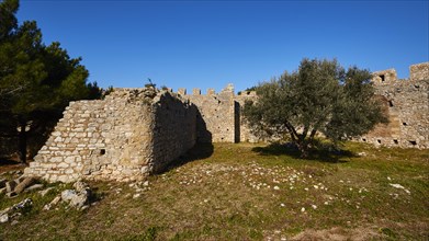 Part of the fortress wall surrounded by trees and grass, Chlemoutsi, High Medieval Crusader castle,
