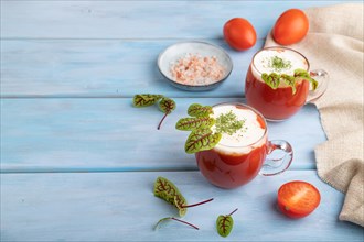 Tomato juice with sorrel, himalayan salt and sour cream in glass on blue wooden background with