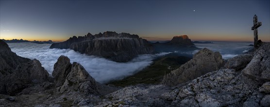 Summit cross of the large Cirrspitze with sunrise over a sea of fog and Dolomite peaks in the