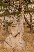 Stone carved statue of Buddhist deity in front of white wall in garden in South Korea