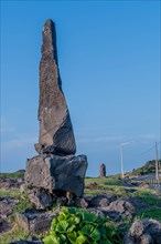 Tall volcanic rock formation in rock park with blue sky in background in Jeju, South Korea, Asia