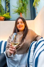Vertical portrait of a woman holding a glass of wine in a cafeteria