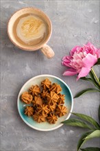 Homemade soft caramel fudge candies on blue plate and cup of coffee on gray concrete background,